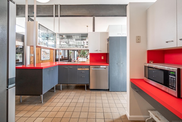 kitchen with light tile patterned flooring, a sink, white cabinetry, and appliances with stainless steel finishes