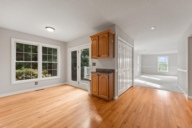 40 Nathan Hale Ct, Cheshire, CT 06410 - kitchen featuring brown cabinets, light wood finished floors, open floor plan, baseboards, and a textured ceiling