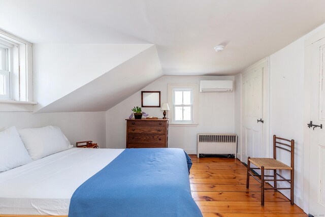 265 Housatonic River Rd, Salisbury, CT 06068 - bedroom with radiator, vaulted ceiling, hardwood / wood-style flooring, and a wall mounted air conditioner