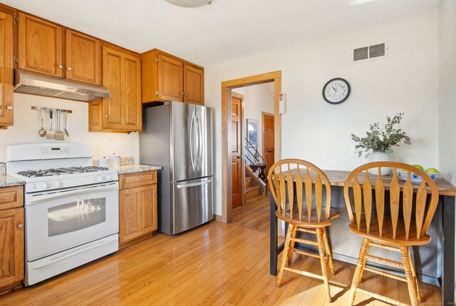 93 Lyman Rd, West Hartford, CT 06117 - kitchen with gas range gas stove, freestanding refrigerator, under cabinet range hood, light wood-type flooring, and visible vents