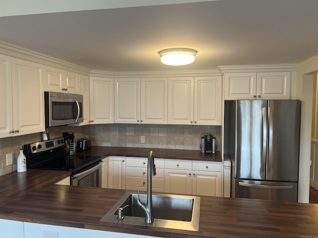 kitchen featuring butcher block countertops, a sink, backsplash, and appliances with stainless steel finishes