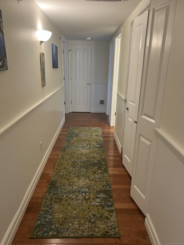 hall with baseboards, dark wood-style floors, and visible vents