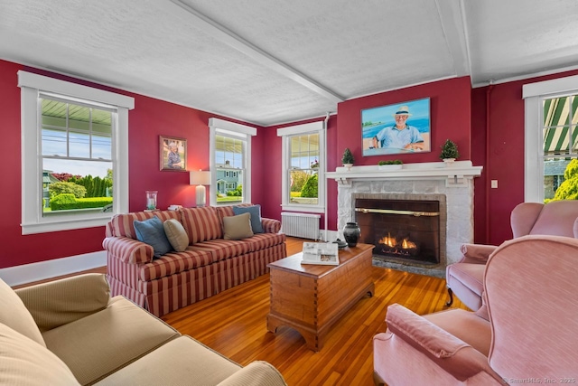 86 Tyler Ave, Groton, CT 06340 - living room with radiator heating unit, a brick fireplace, wood finished floors, plenty of natural light, and a textured ceiling