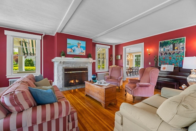 86 Tyler Ave, Groton, CT 06340 - living area featuring a fireplace with flush hearth, wood finished floors, a chandelier, and radiator heating unit