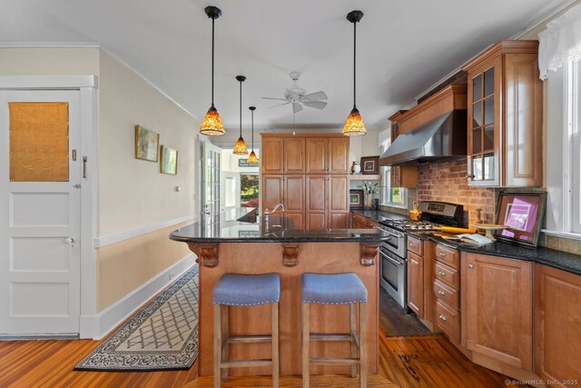 86 Tyler Ave, Groton, CT 06340 - kitchen featuring double oven range, wall chimney range hood, a ceiling fan, wood finished floors, and a kitchen bar