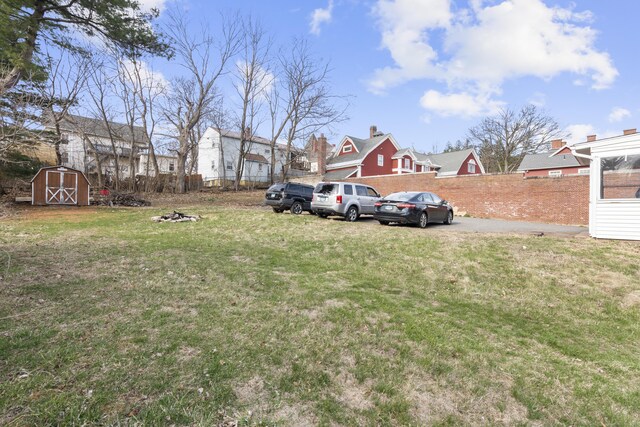 view of yard with an outdoor structure, fence, and a storage shed