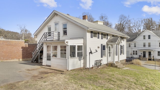 back of property featuring a chimney, a yard, stairway, and entry steps