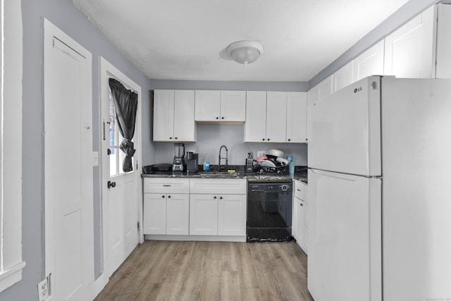 kitchen featuring light wood finished floors, black dishwasher, white cabinetry, a sink, and freestanding refrigerator