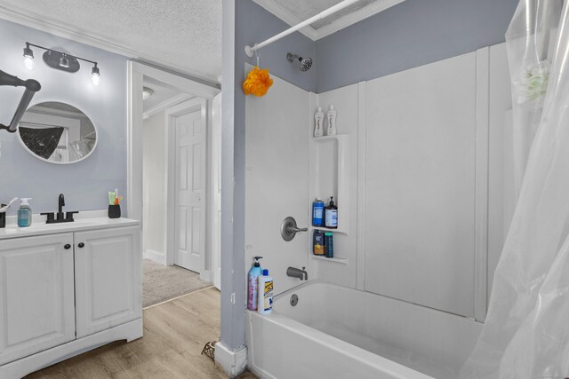 bathroom with wood finished floors, shower / tub combo with curtain, ornamental molding, and a textured ceiling