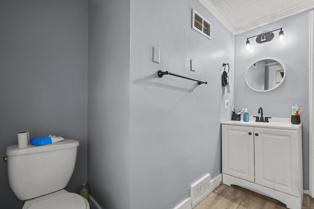 bathroom with a textured ceiling, visible vents, toilet, and wood finished floors