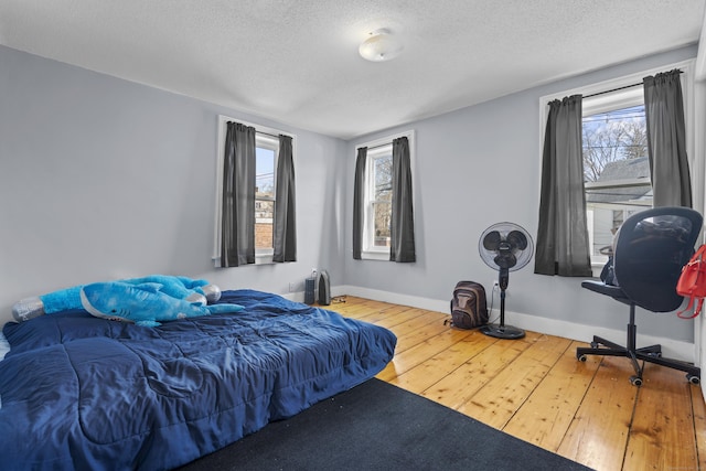 bedroom with hardwood / wood-style flooring, baseboards, and a textured ceiling