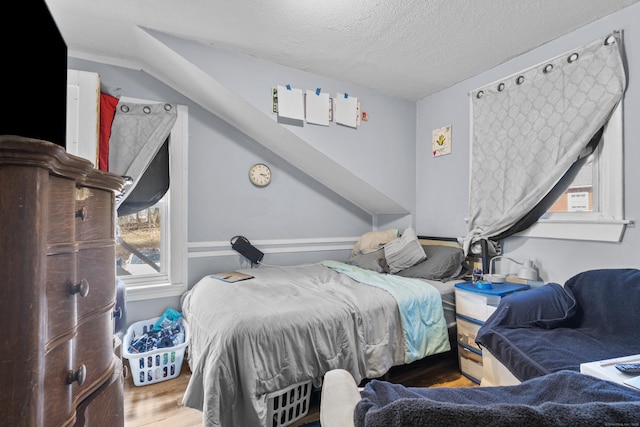 bedroom featuring a textured ceiling, wood finished floors, and multiple windows