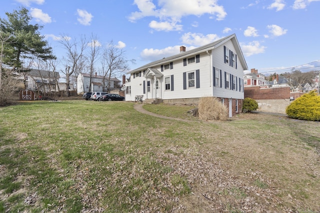 rear view of property featuring entry steps, a yard, and a chimney