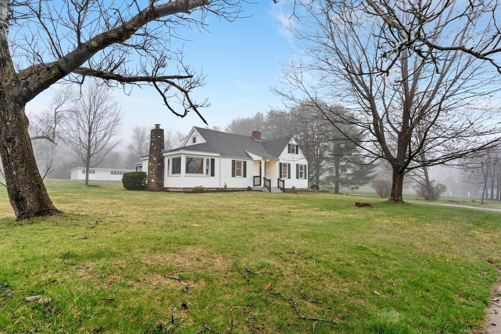 view of front facade featuring a front lawn and a chimney