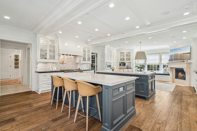 358 Lukes Wood Rd, New Canaan, CT 06840 - kitchen featuring a spacious island, gray cabinetry, a warm lit fireplace, hardwood / wood-style floors, and crown molding