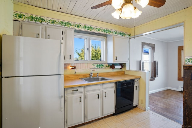 kitchen featuring a baseboard radiator, light countertops, a sink, freestanding refrigerator, and black dishwasher