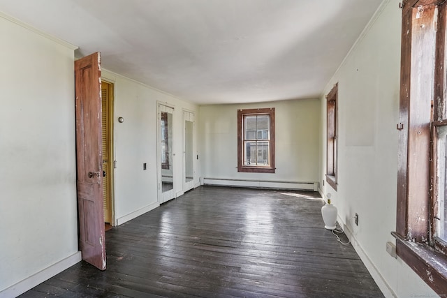 empty room featuring hardwood / wood-style floors, crown molding, baseboards, and baseboard heating