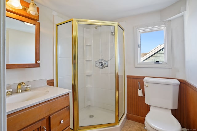full bath featuring a wainscoted wall, toilet, and a shower stall