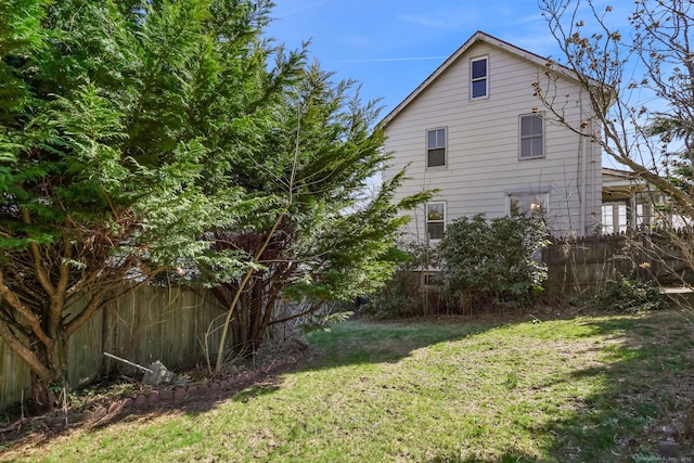view of home's exterior featuring a lawn and fence