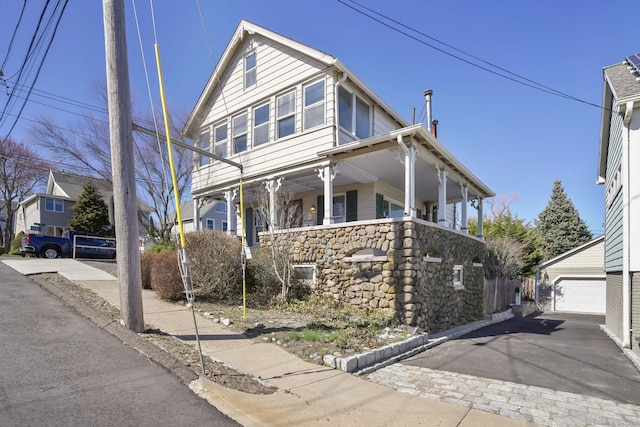 view of front facade with stone siding and an outbuilding