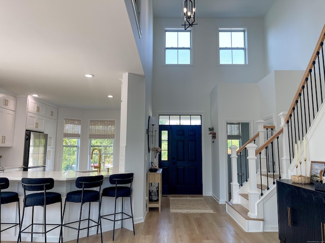 foyer entrance featuring light wood finished floors, a high ceiling, a wealth of natural light, and stairway