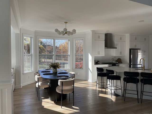 dining area with crown molding, baseboards, an inviting chandelier, and light wood-style flooring