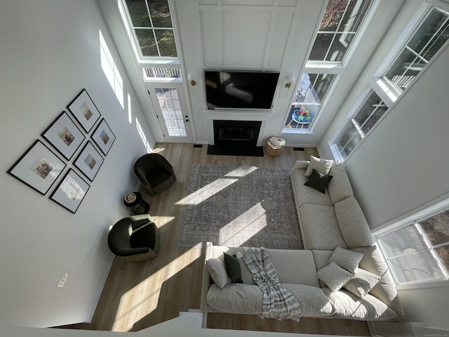 living area with a high ceiling, a fireplace with flush hearth, and wood finished floors