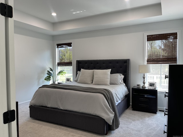 bedroom featuring recessed lighting, a tray ceiling, and light colored carpet