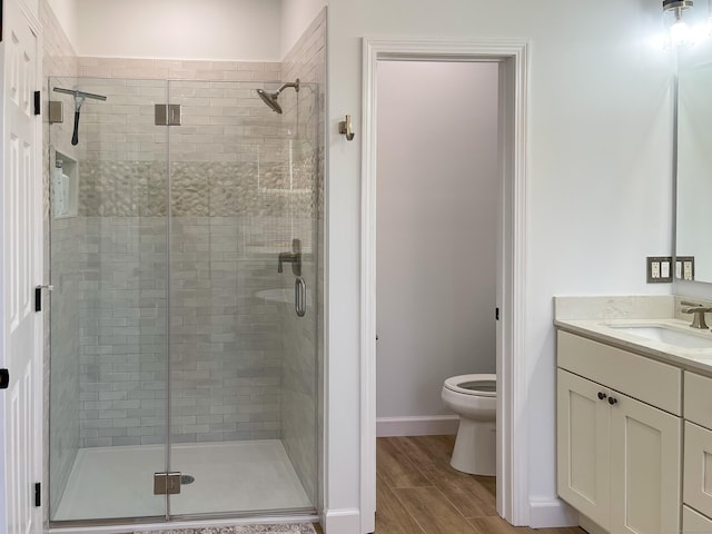 full bathroom with vanity, a shower stall, toilet, and wood finished floors