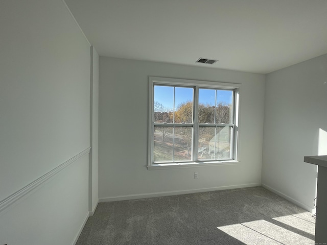 carpeted spare room featuring baseboards and visible vents