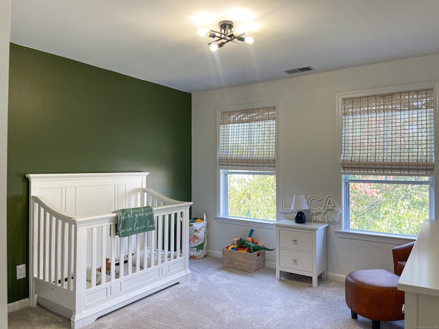 carpeted bedroom with baseboards, a crib, and visible vents