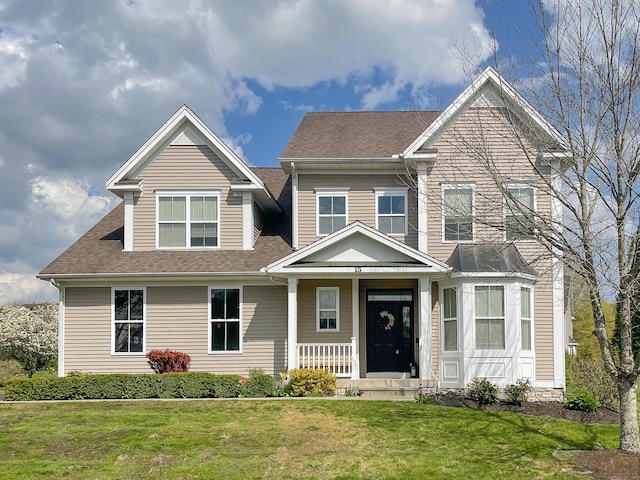 craftsman inspired home featuring a front lawn, roof with shingles, and covered porch