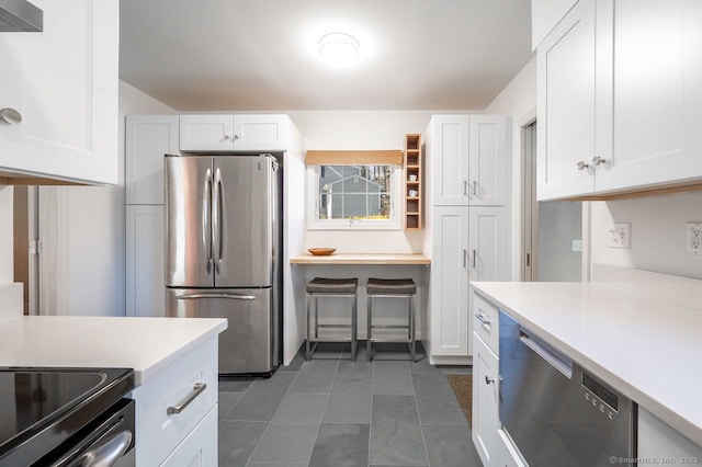 kitchen with stainless steel appliances, light countertops, white cabinetry, and wall chimney range hood