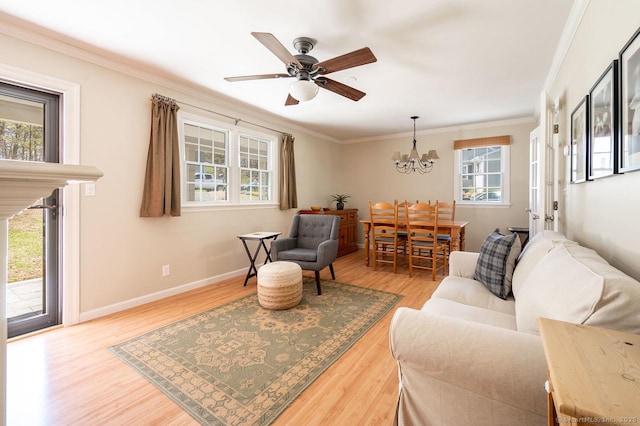living area featuring ceiling fan with notable chandelier, baseboards, wood finished floors, and crown molding
