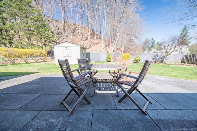 view of patio / terrace featuring a fenced backyard, outdoor dining space, a shed, an outdoor structure, and a mountain view