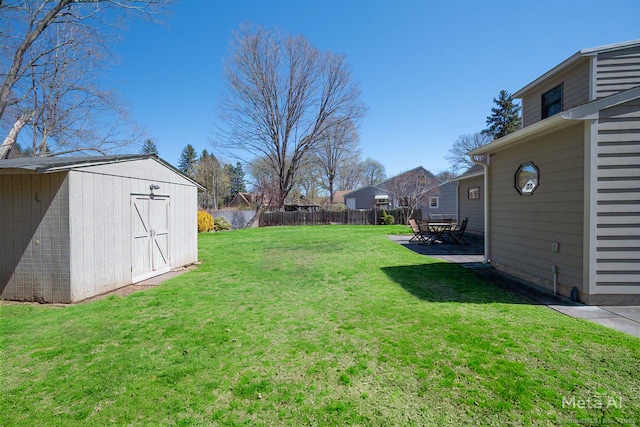 view of yard with an outbuilding, a shed, a patio, and fence