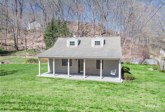 view of front of property featuring a porch, a chimney, roof with shingles, and a front yard