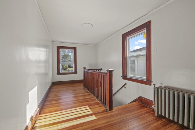 interior space with radiator heating unit, baseboards, an upstairs landing, and hardwood / wood-style flooring