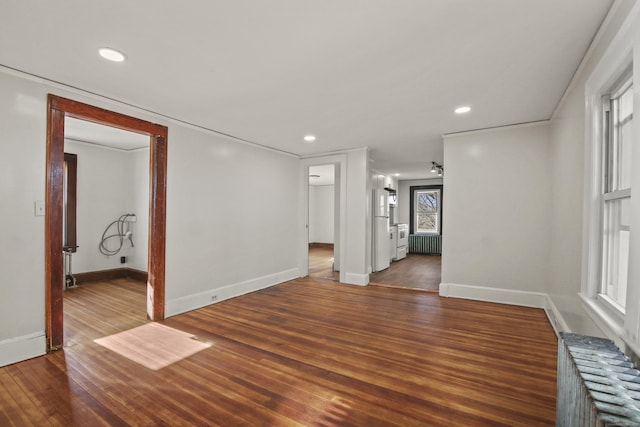 empty room with recessed lighting, radiator heating unit, wood finished floors, and baseboards