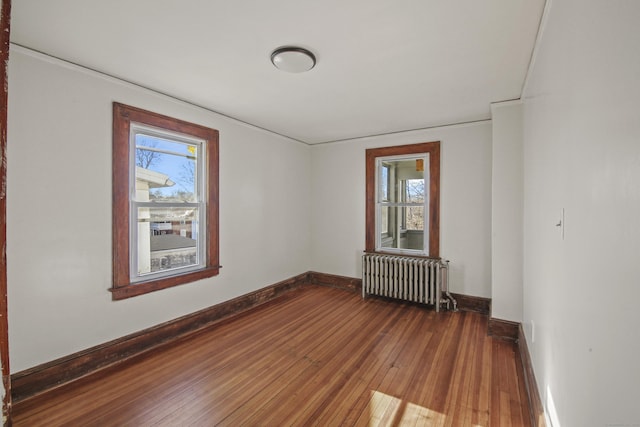 empty room with wood-type flooring, baseboards, and radiator