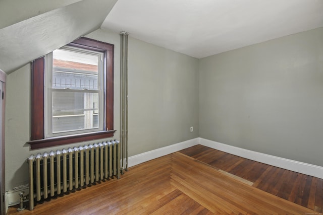 bonus room with radiator heating unit, lofted ceiling, wood finished floors, and baseboards