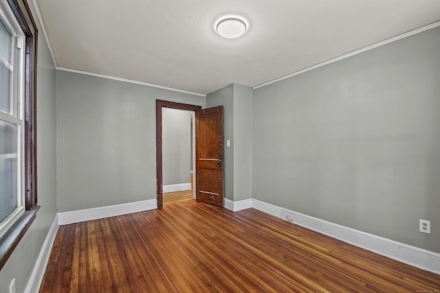spare room with crown molding, wood finished floors, and baseboards