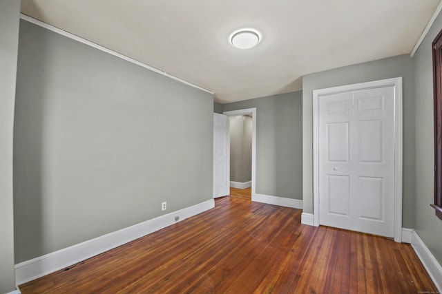 unfurnished bedroom featuring dark wood-style flooring and baseboards