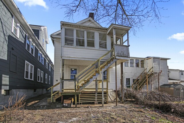 back of property with stairs and a chimney