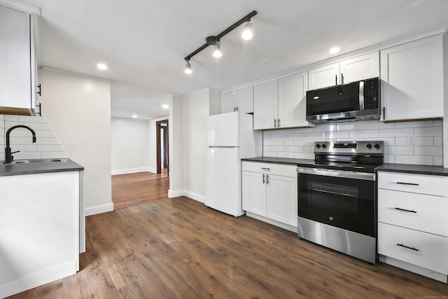 kitchen with baseboards, dark countertops, dark wood-type flooring, stainless steel appliances, and a sink