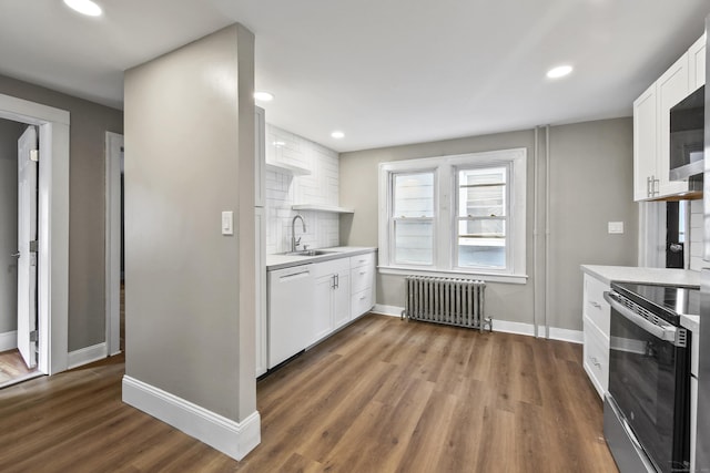 kitchen featuring radiator heating unit, light countertops, a sink, white dishwasher, and range with electric cooktop