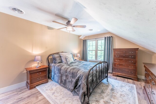 bedroom featuring a ceiling fan, vaulted ceiling, visible vents, light wood finished floors, and baseboards