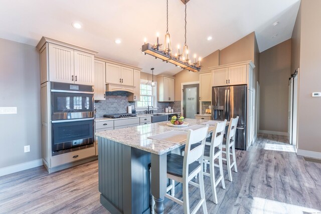 kitchen featuring a center island, a breakfast bar, vaulted ceiling, stainless steel appliances, and decorative backsplash
