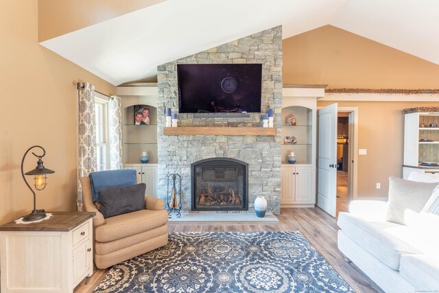 living room with light wood-type flooring, vaulted ceiling, and a fireplace