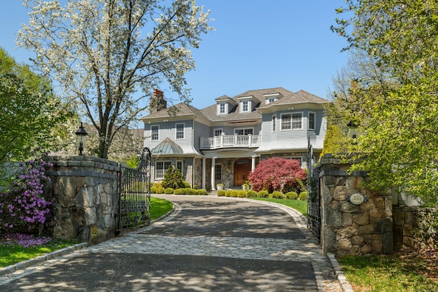 355 Greens Farms Rd, Westport, CT 06880 - view of front facade with stone siding, a gate, a chimney, a balcony, and curved driveway